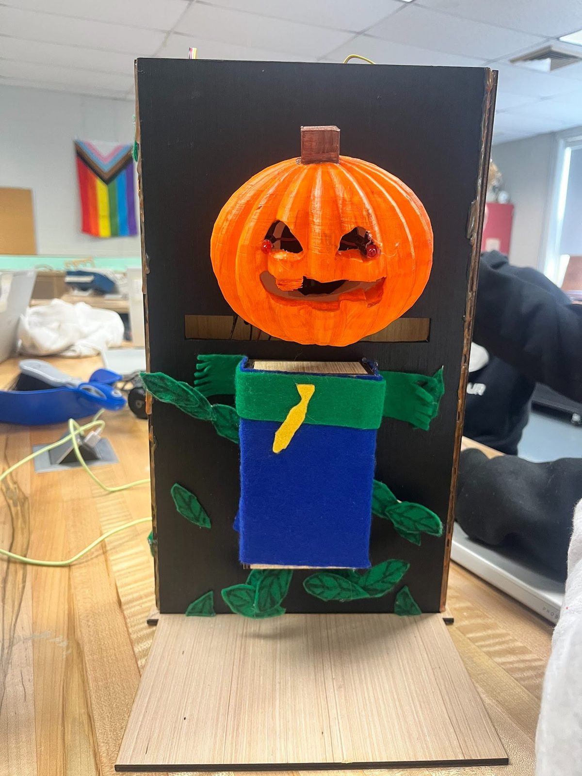 Animatronic jack-o'-lantern scarecrow prop with glowing eyes and a felt scarf and vest