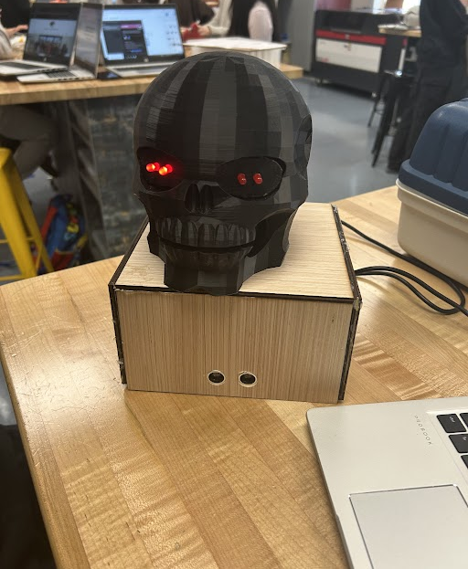 3D-printed skull prop with glowing red LED eyes mounted on a wooden box