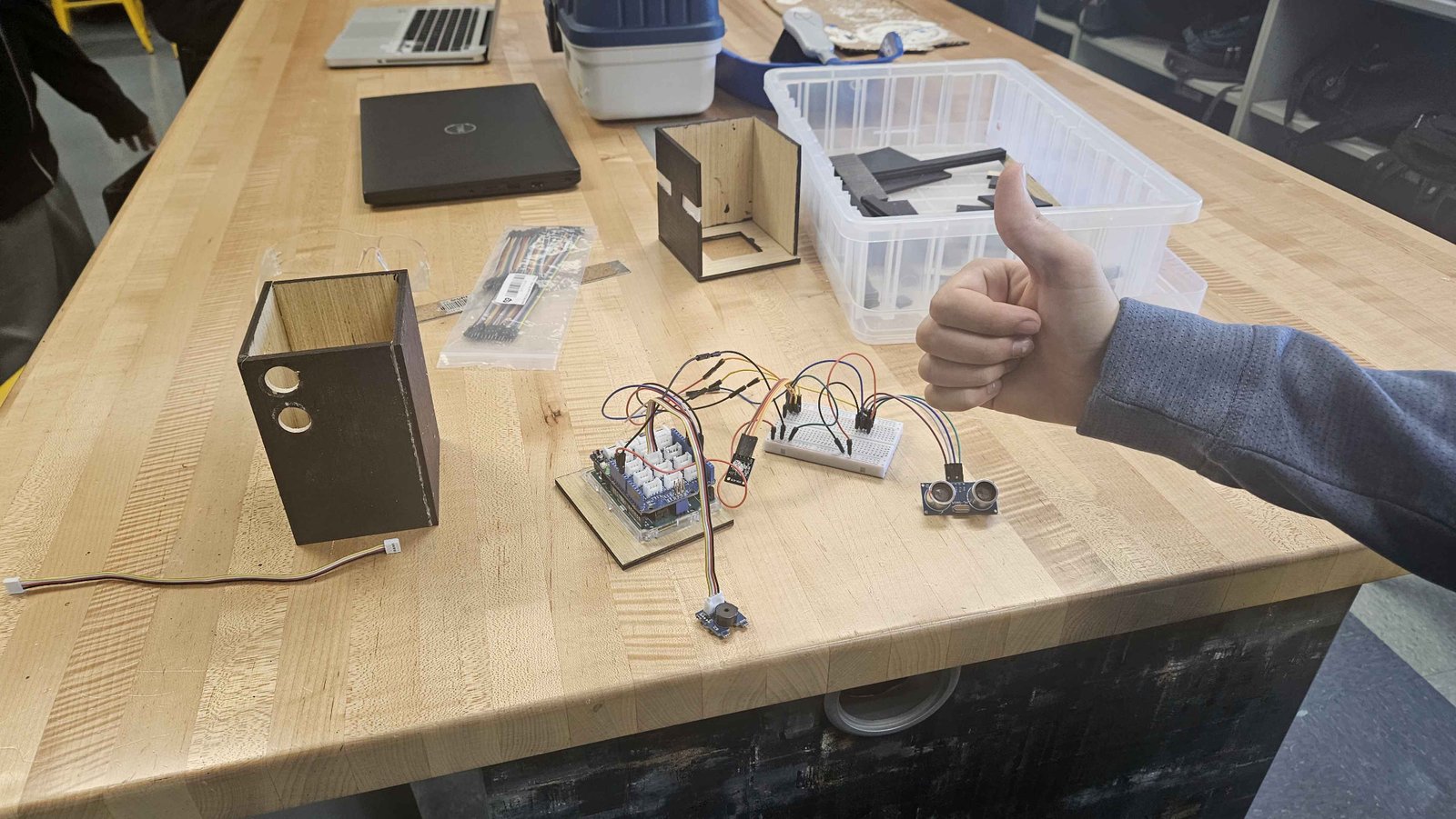 Arduino, breadboard, and ultrasonic sensor wired up next to a laser-cut project box