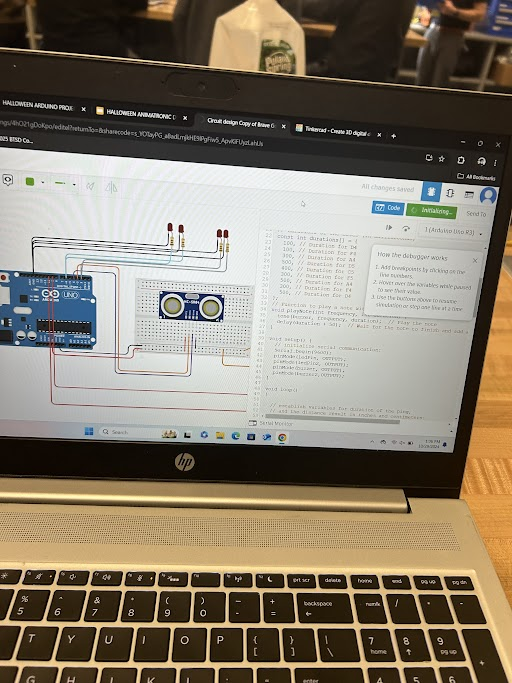 Laptop screen showing Arduino wiring diagram and code for the animatronic project
