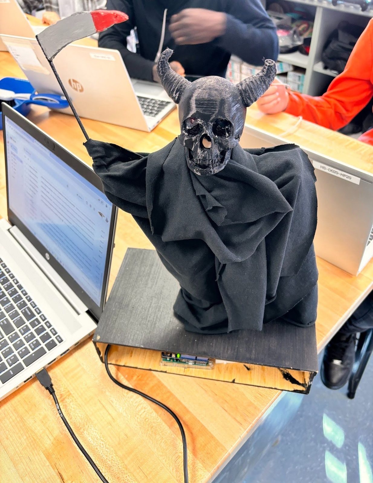 Animatronic horned skeleton figure in a black robe holding a scythe