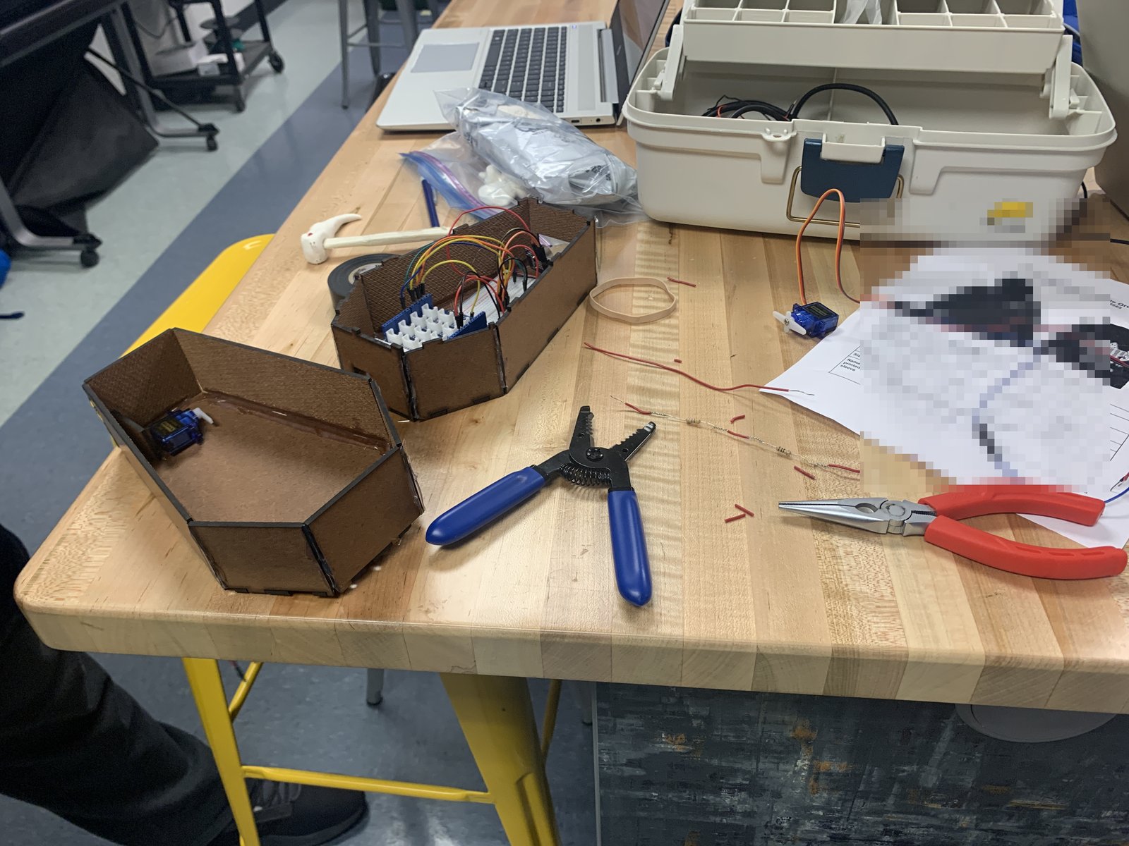 Servo motor and wiring laid out on a workbench with wire strippers and pliers
