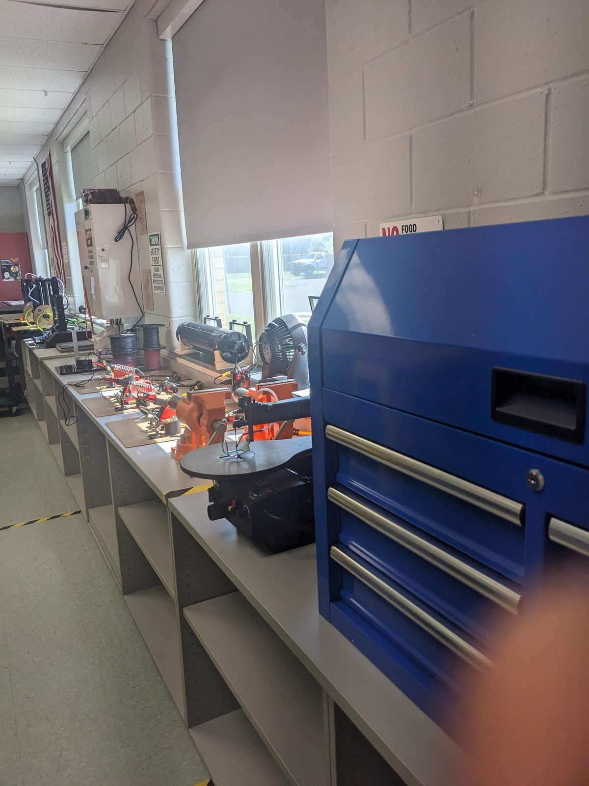 After: a workbench along the window wall with a scroll saw, vises, and a rolling tool chest