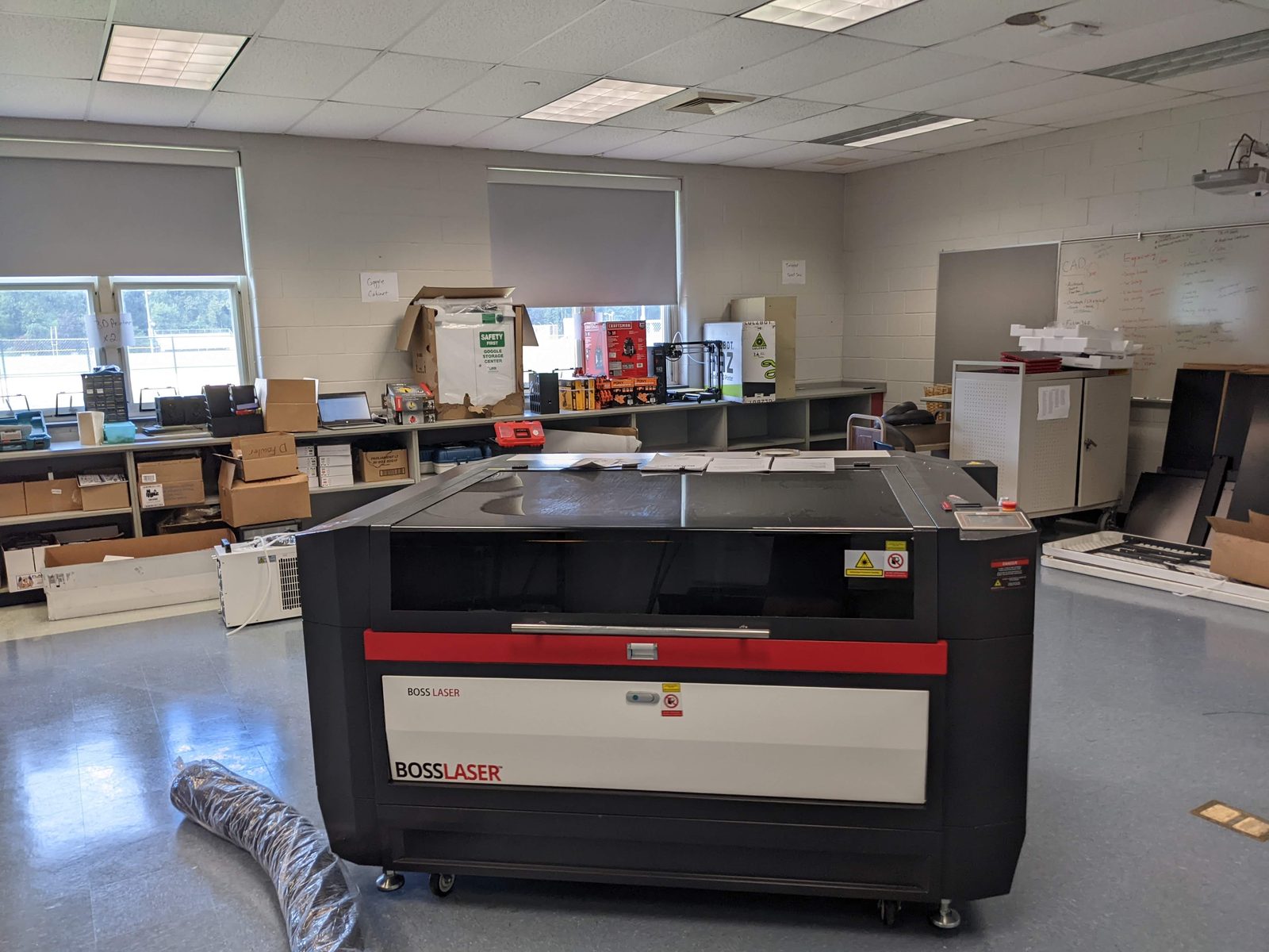 A new laser cutter freshly installed in the lab during move-in, surrounded by unpacked boxes