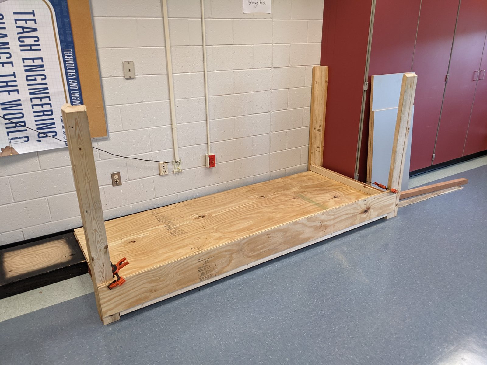 A plywood storage rack under construction against the classroom wall