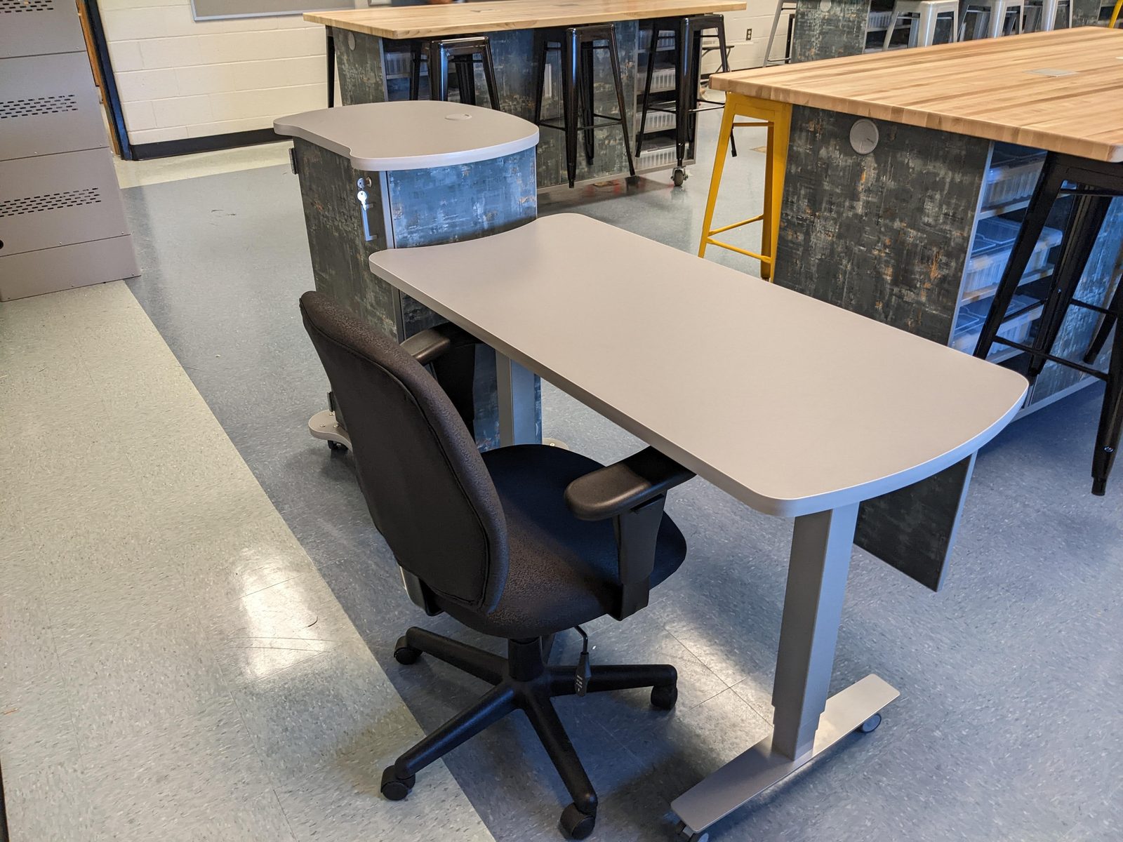After: the teacher's adjustable-height desk beside the finished pod desks