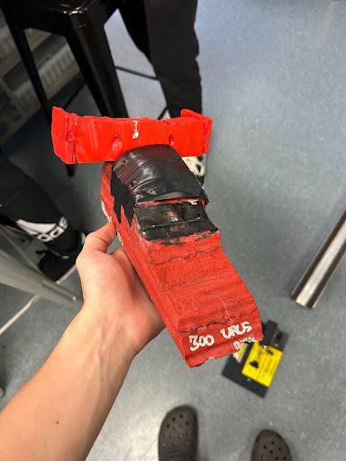 Red CO2 car with a large rear spoiler and '300 WHP' written on the side, held in hand