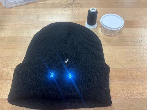 Black beanie with two blue LEDs embedded in the brim, lit up
