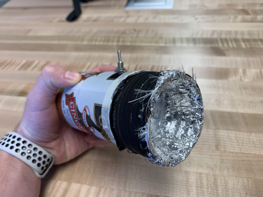 Hand holding a flashlight built from a soda can with a foil reflector cone