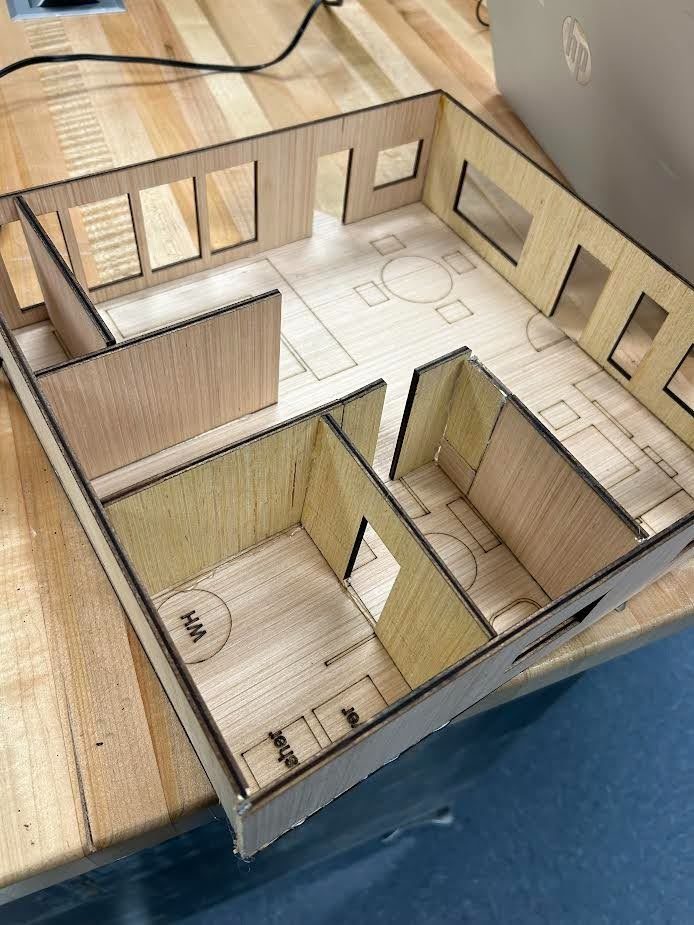 Laser-cut wood model interior showing bedroom partitions and a bathroom layout
