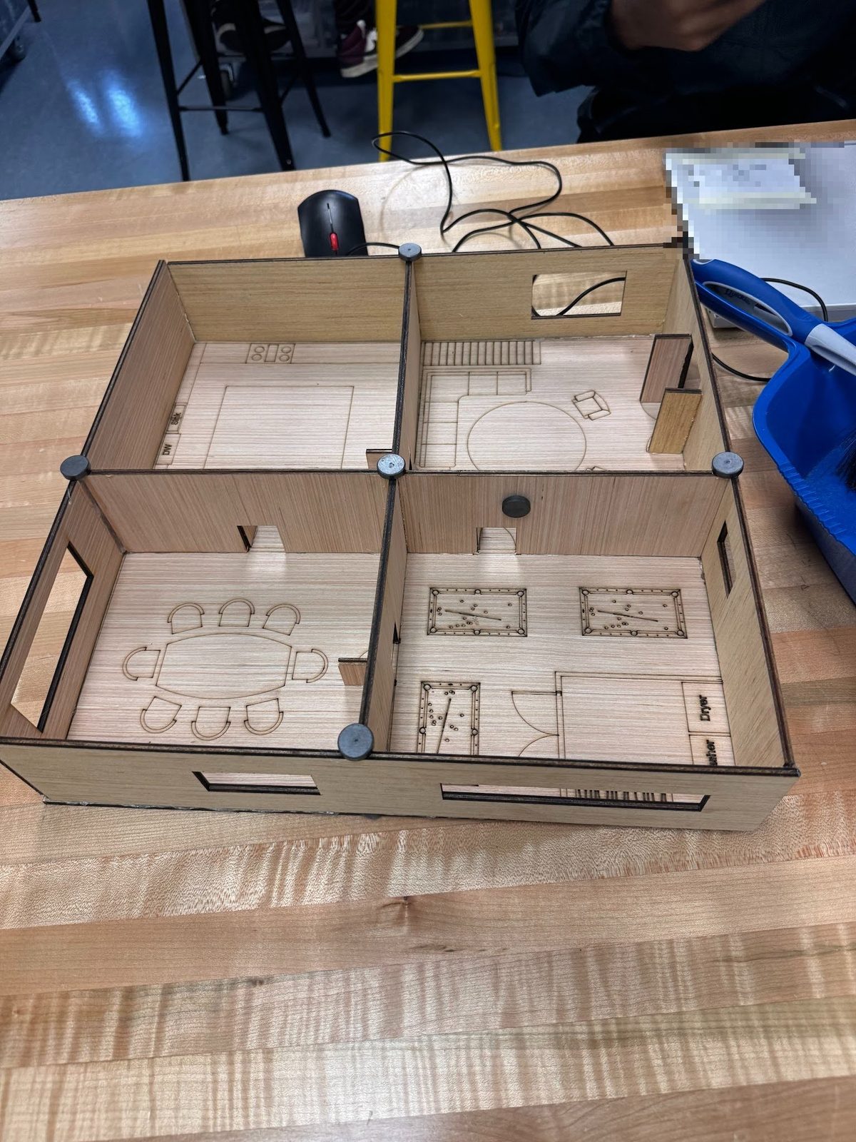 Laser-cut house model under construction on a workbench