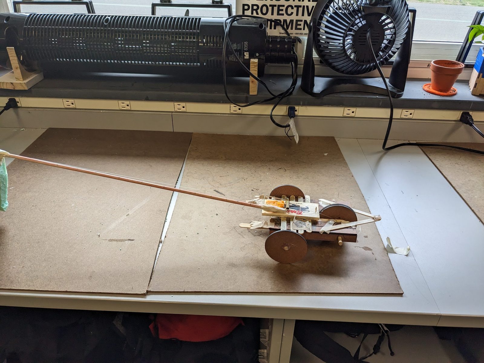 Mousetrap car with an extended lever-arm axle, parked near a windowsill