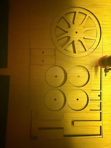 Laser-cut mousetrap car wheels and chassis pieces still on the laser bed