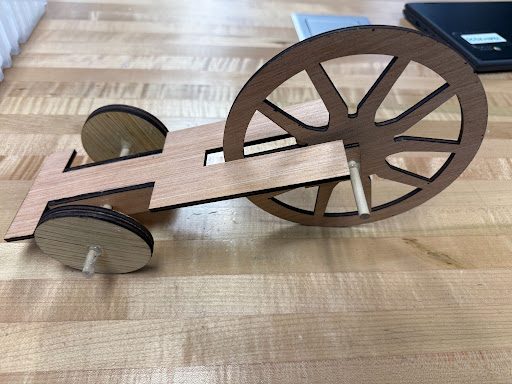 Assembled mousetrap car chassis with a large rear wheel and small front wheels