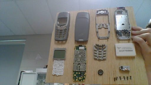Classic Nokia phone fully disassembled and laid out on a wooden board