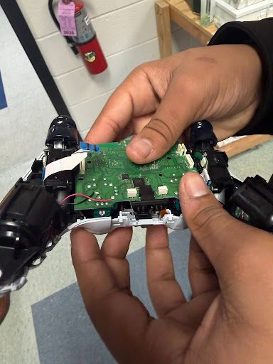 Student holding the disassembled game controller's circuit board close up
