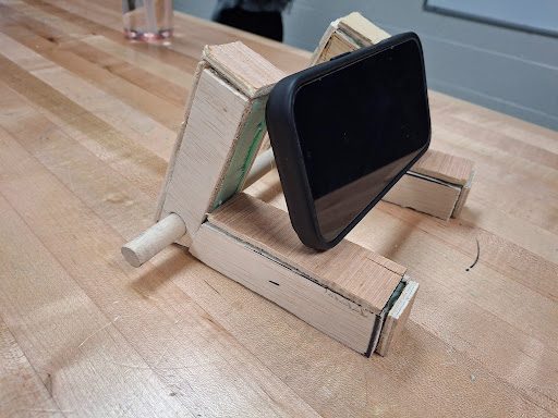 Wooden kickstand-style phone stand holding a phone at an angle
