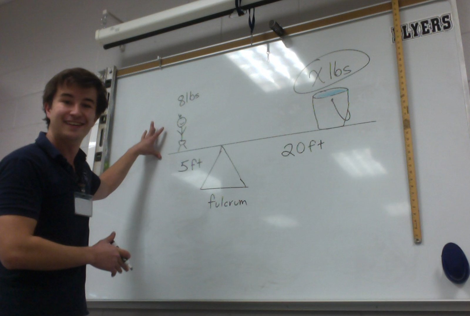 Dalton Fowler pointing to a lever and fulcrum diagram on the whiteboard at Millstone Middle School