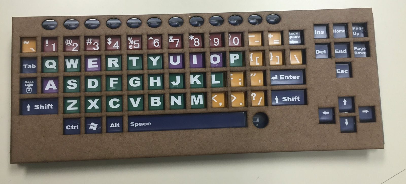 Laser-cut wooden keyboard cover with color-coded, high-contrast keys for an assistive keyboard
