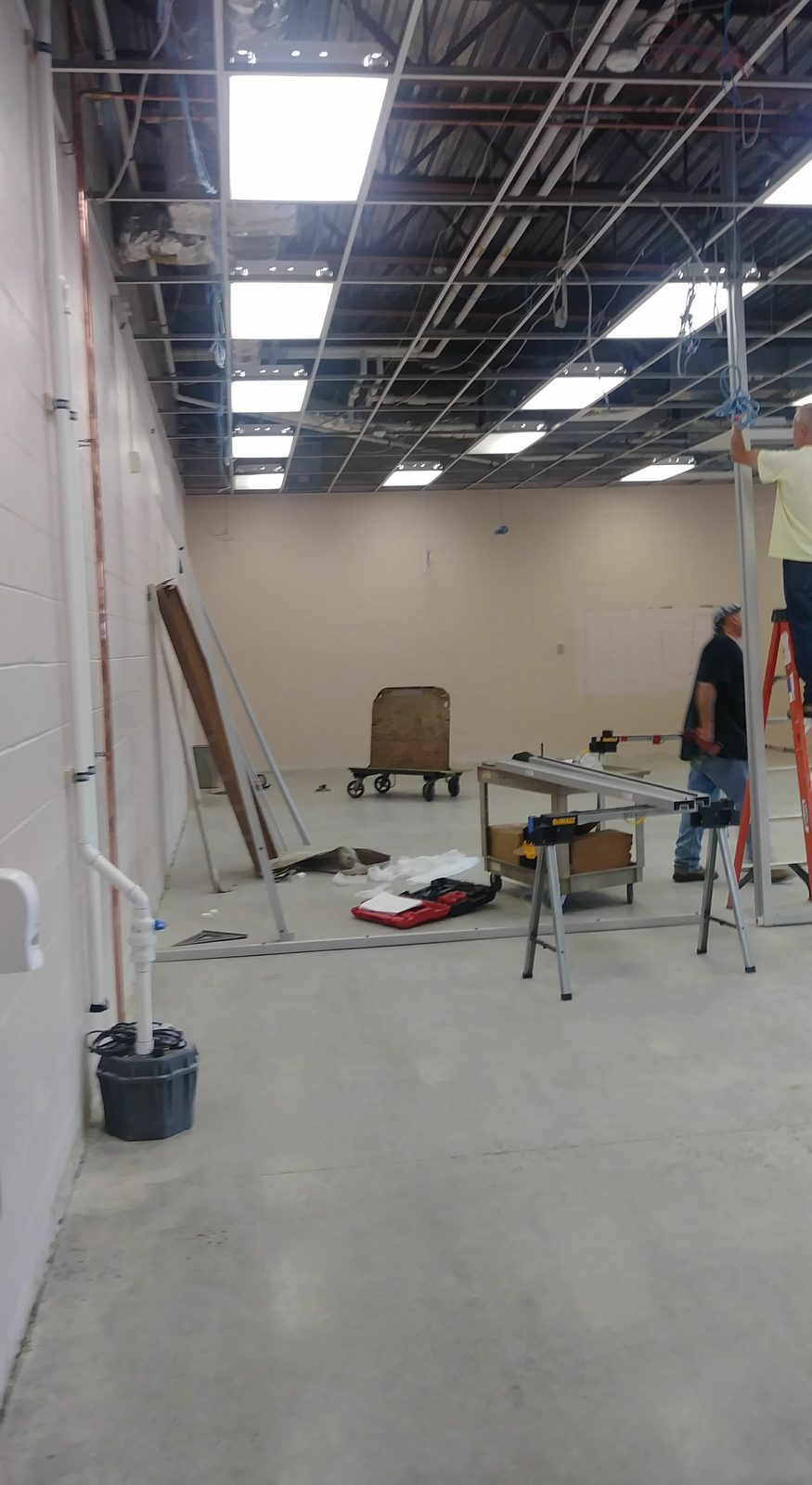 Lab space mid-construction, with ladders, tools, and workers framing out the ceiling grid