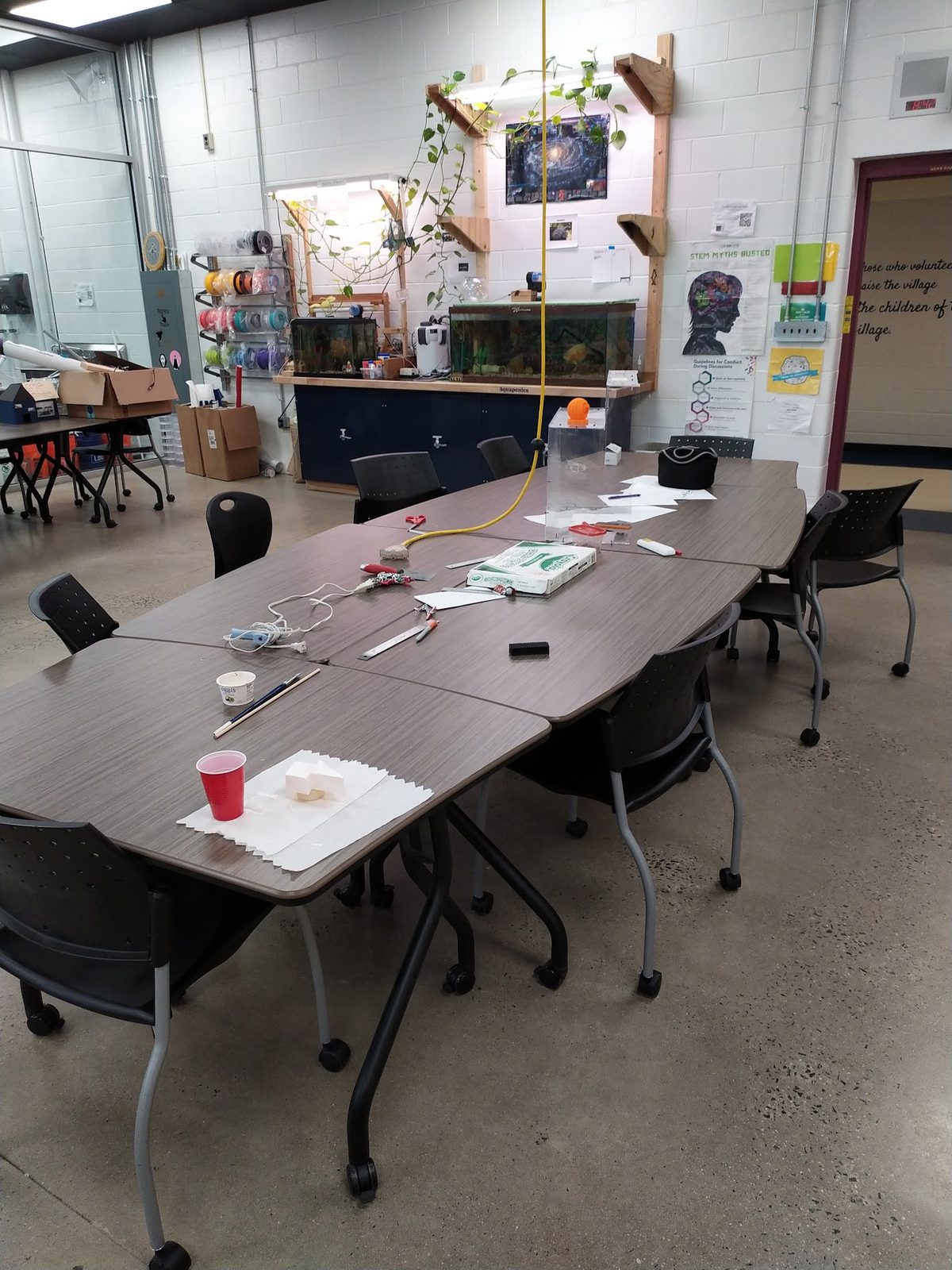 Classroom tables in front of a second-generation classroom aquaponics tank and filament rack