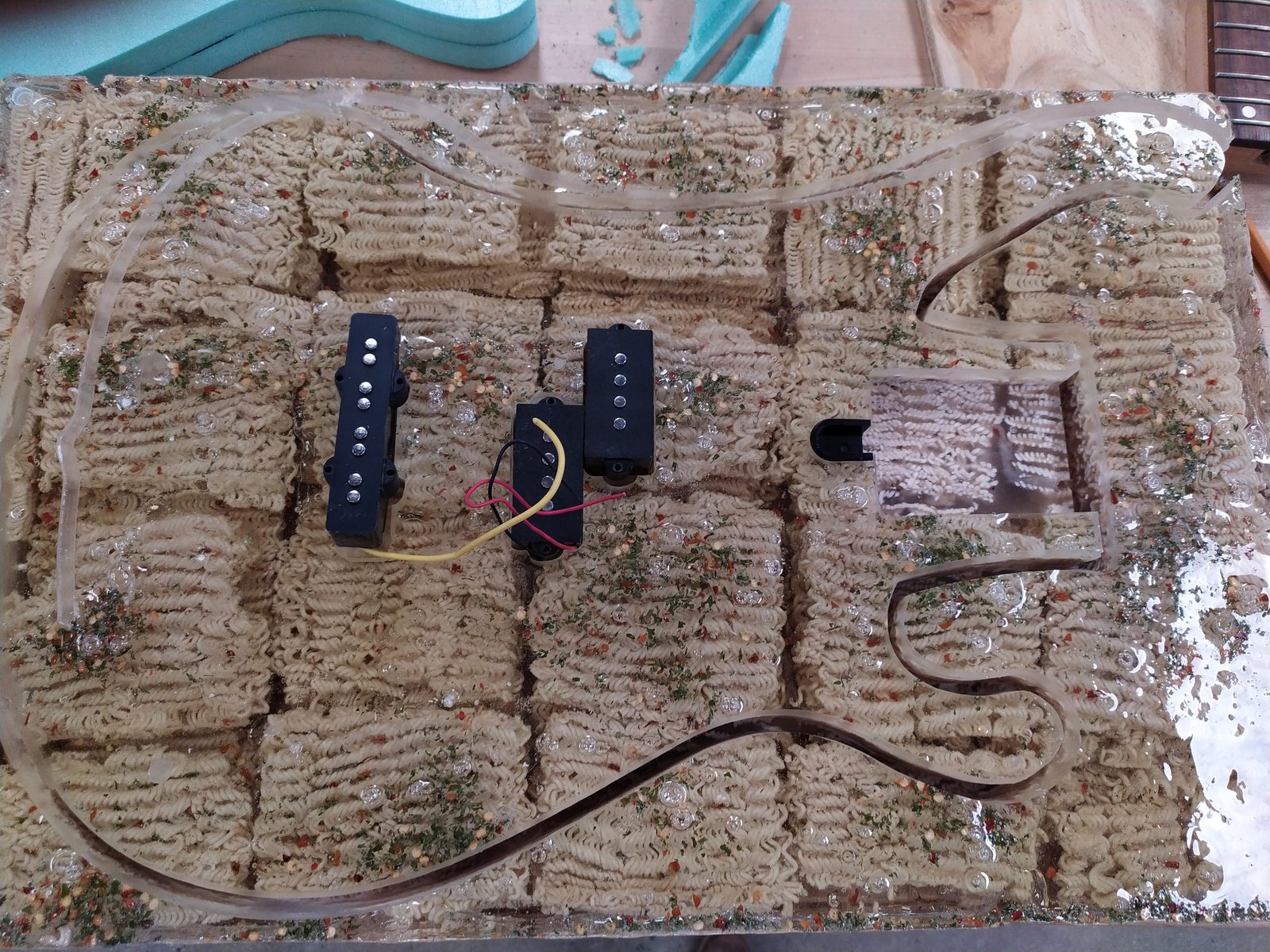 CNC-routed resin guitar body embedded with ramen noodles, with pickups installed