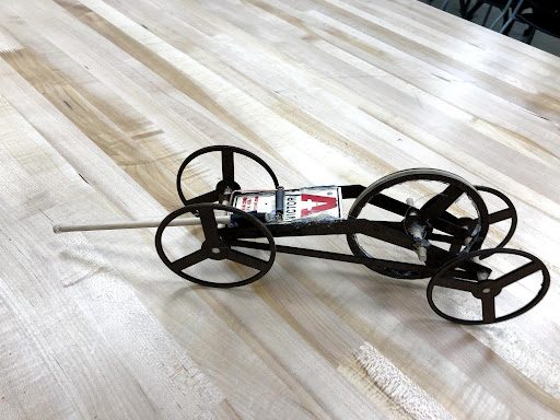 Laser-cut mousetrap car with spoked wheels on a wooden table