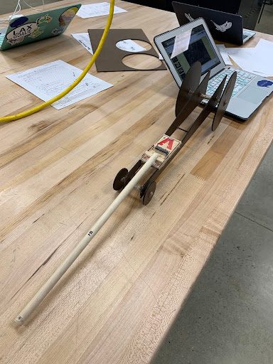 Mousetrap car with a long wooden dowel lever arm extended across the table