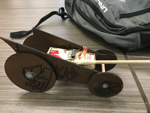 Finished mousetrap car with laser-etched wheel graphics of grasping hands