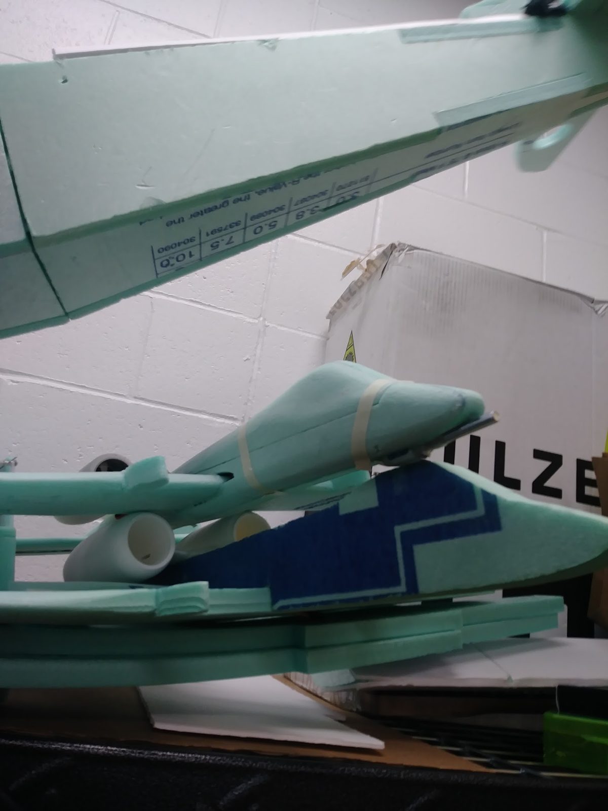 Close-up of the foam RC plane's nose cone and wing structure on the workbench