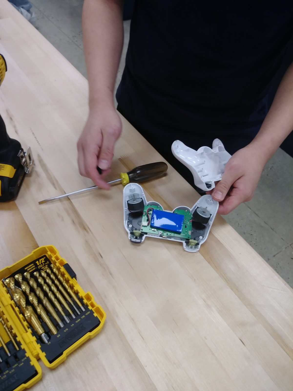 Student taking apart a game controller to expose its motors, battery, and circuit board