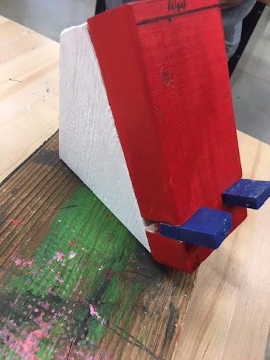 A red and white wooden phone stand with blue wedge supports