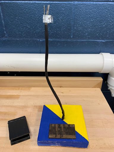 A blue and yellow painted wooden phone stand with a wireless charging coil wired up through the base