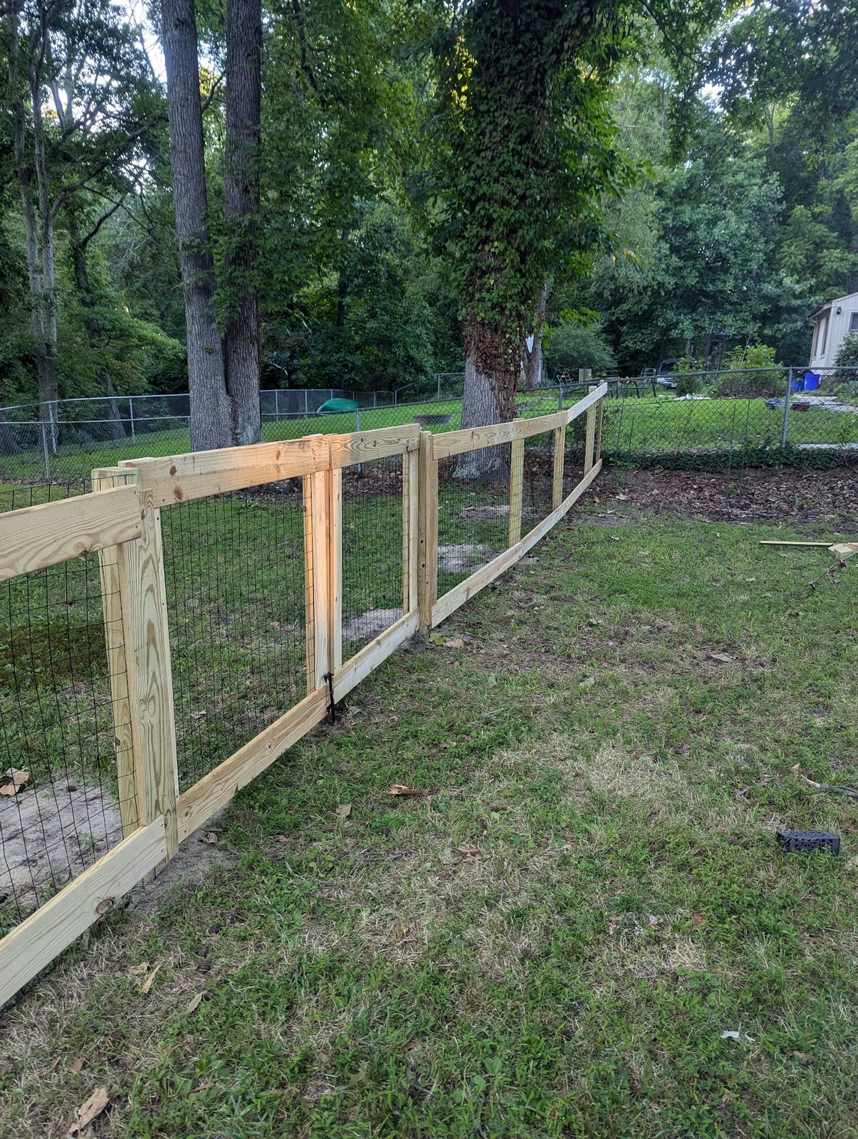 New wire gate and fence panel installed in the grass