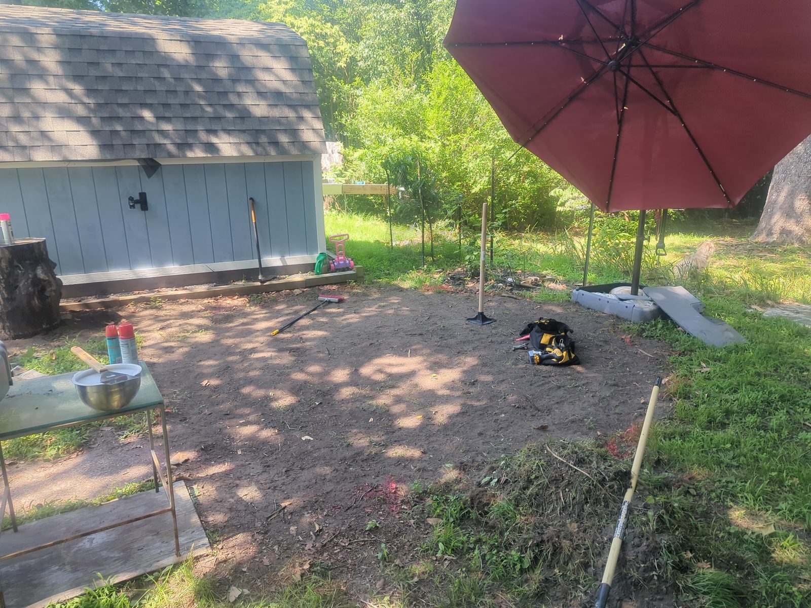 Shed and patio umbrella set up over a gravel seating area