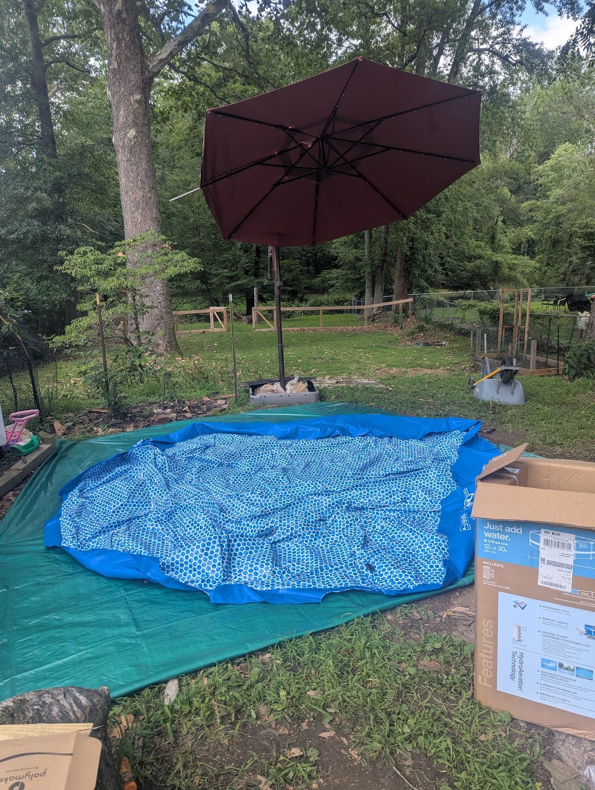 Above-ground pool cover staged next to the patio umbrella