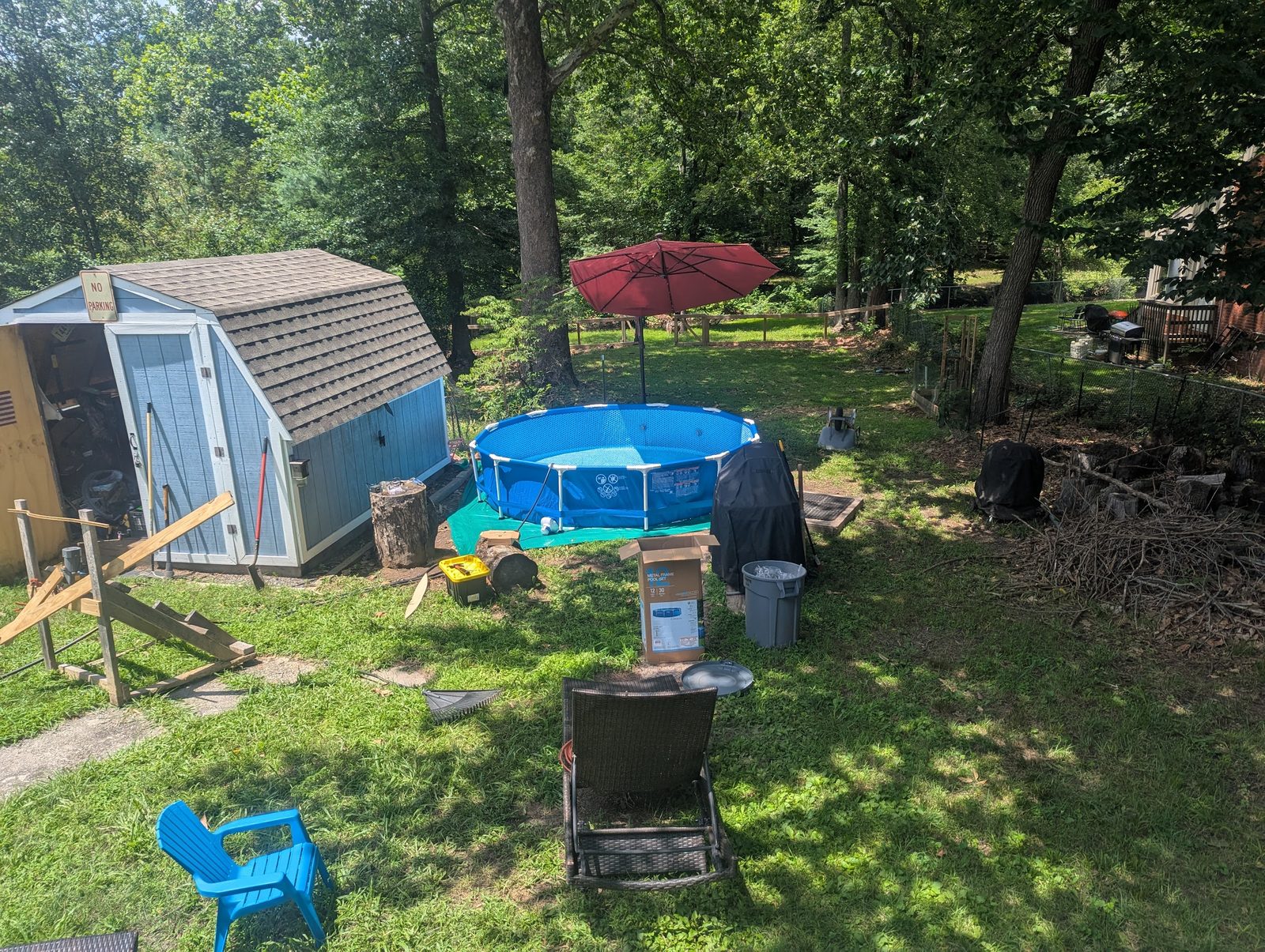 Shed, pool, and umbrella set up together in the backyard