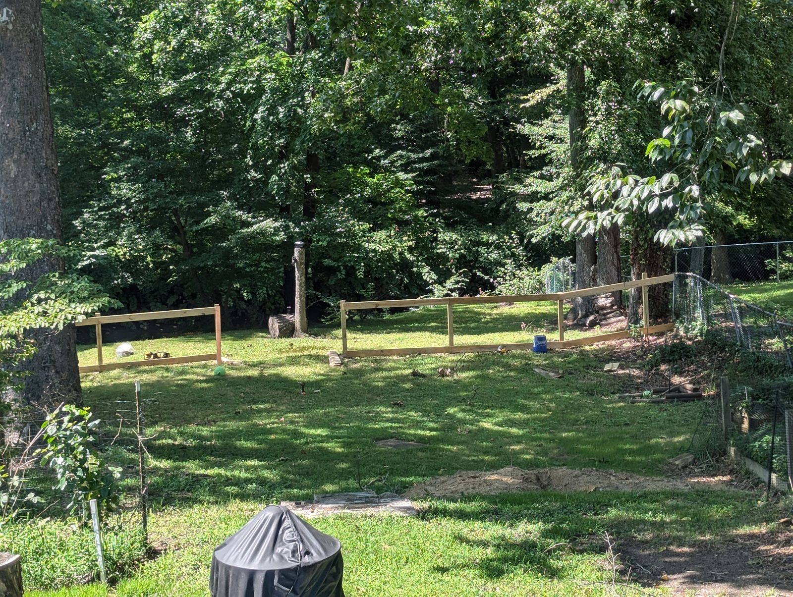 Split-rail and wire fence enclosing a section of the backyard lawn