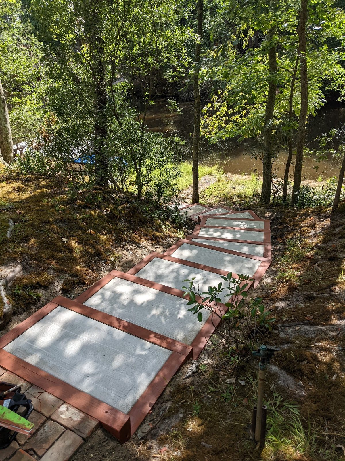 Finished run of concrete steps framed in stained wood, leading down through the woods