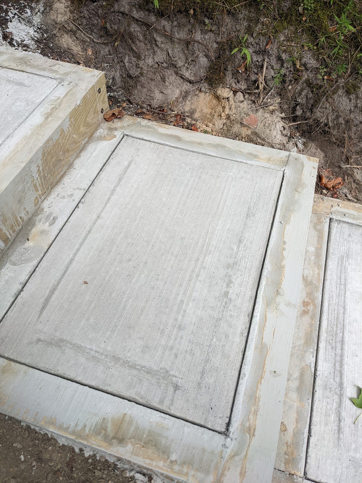 A second concrete step framed in stained wood, further down the path