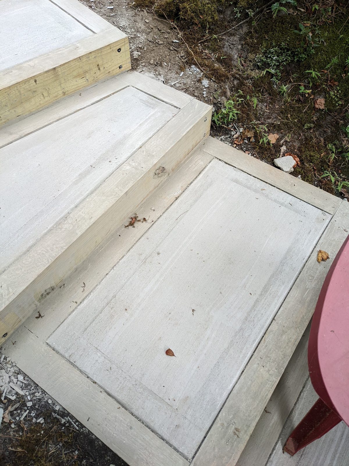 Concrete steps framed in stained wood, continuing down the slope toward the creek