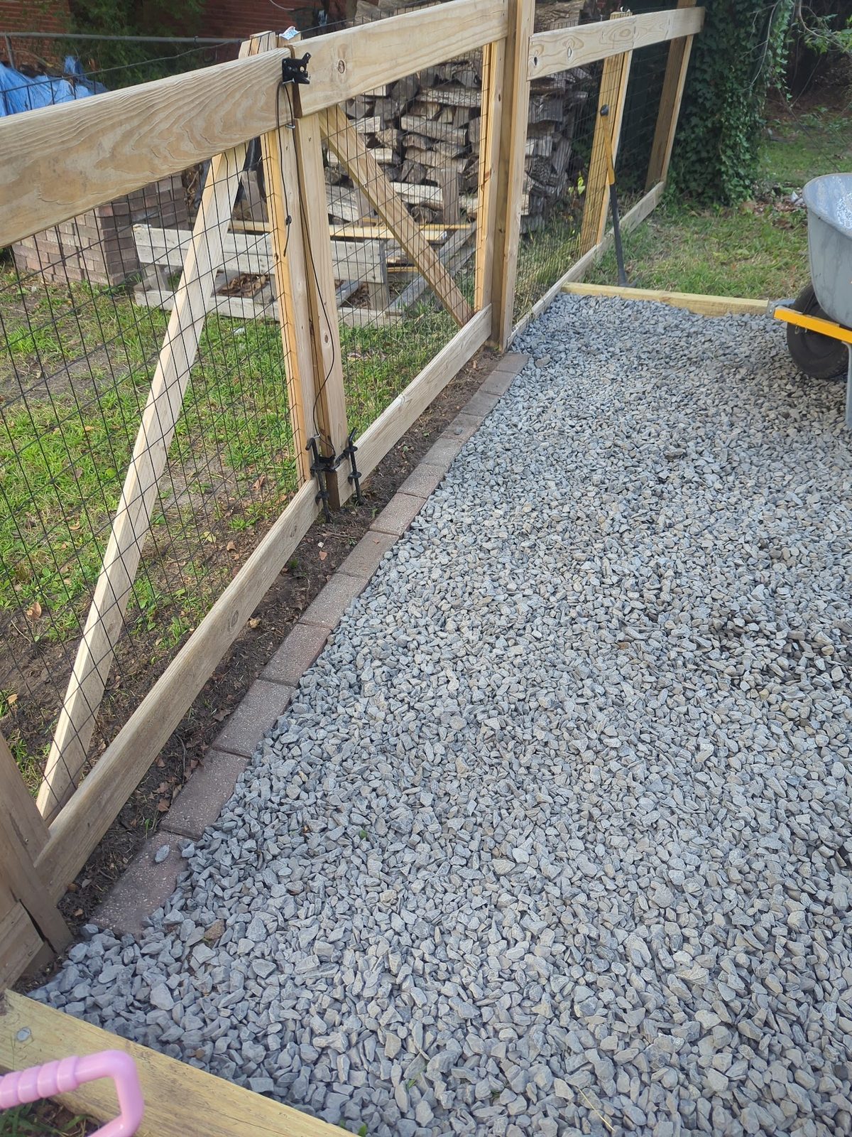 New wire fence and gate framing along the driveway edge