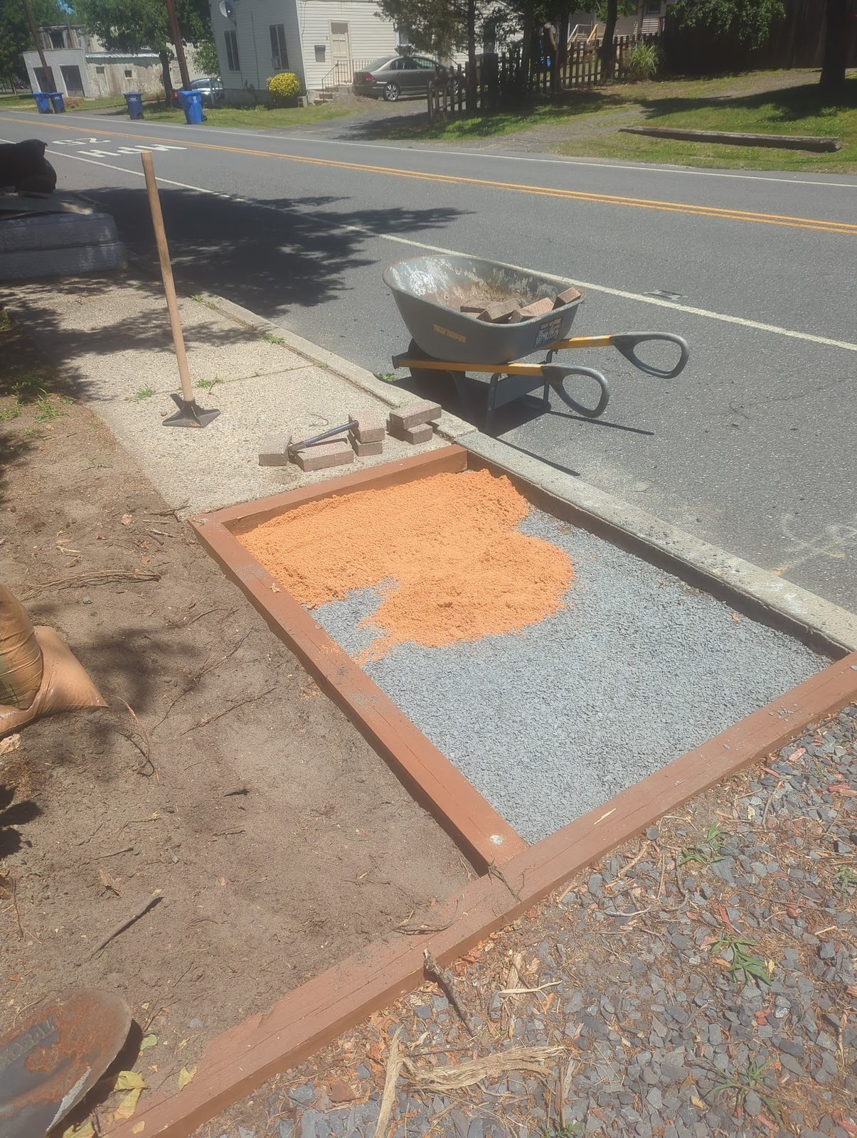 Wheelbarrow and tools next to the walkway's sand base