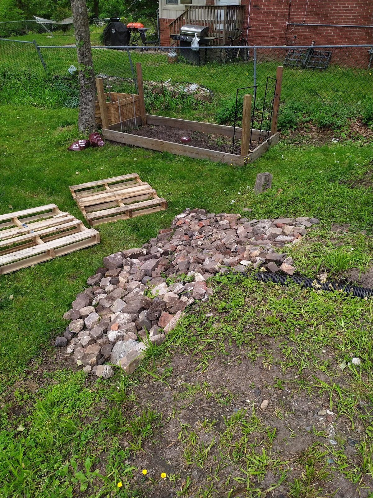 Pile of reclaimed brick and wood pallets staged next to a partially built retaining wall