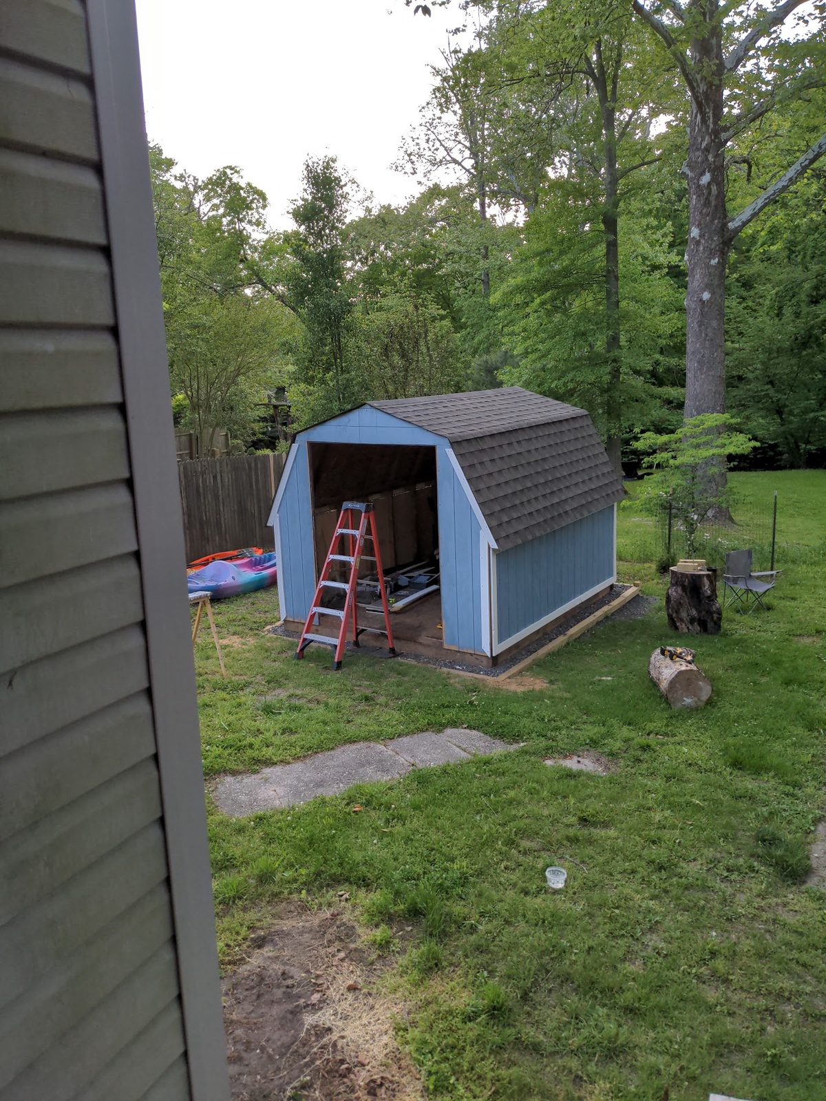 Finished shed painted blue, side view through a gap in the fence
