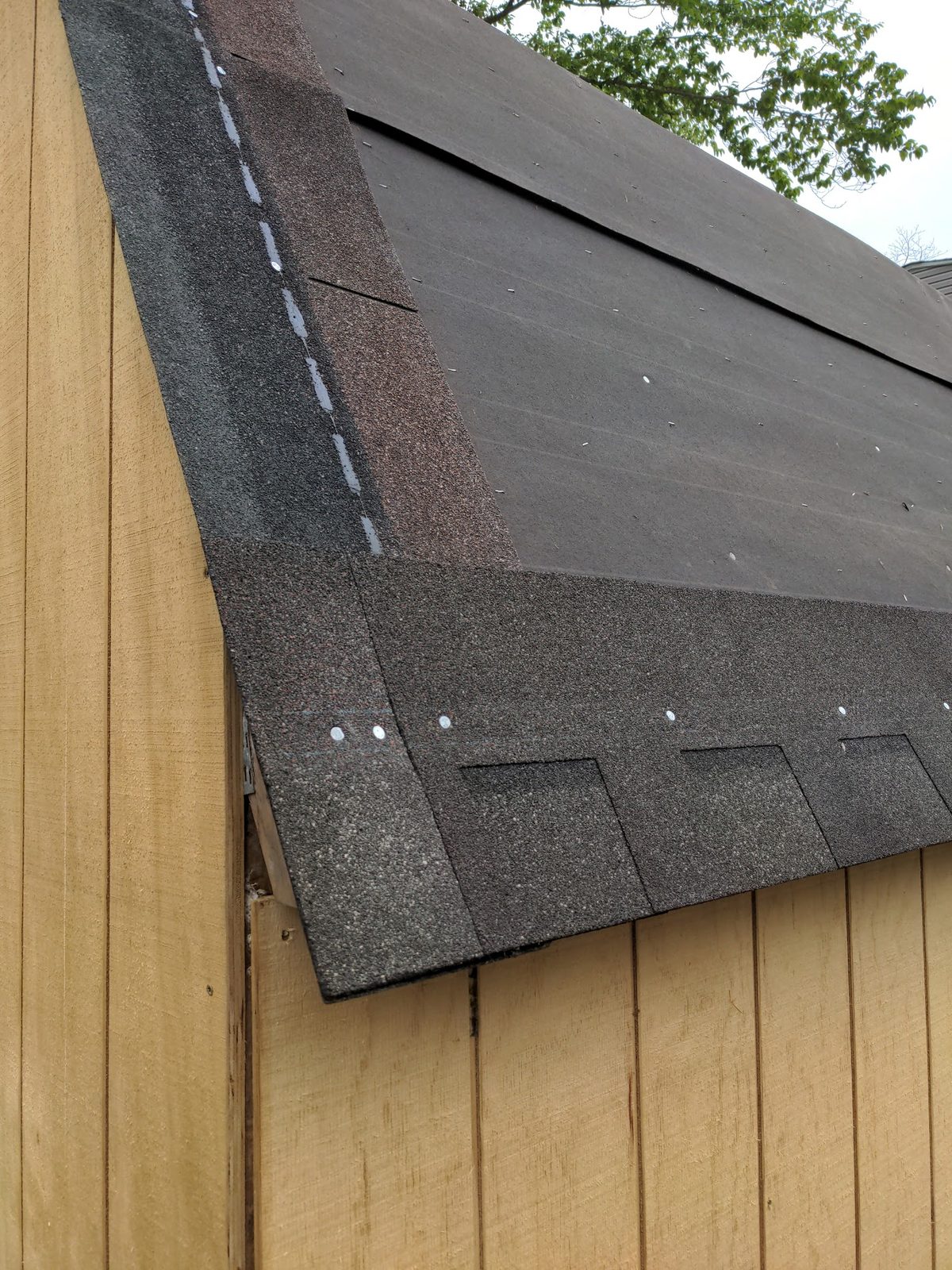 Close-up of shingles being applied along the roof ridge