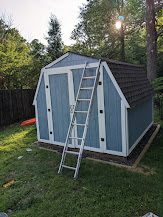 Finished blue shed with a ladder leaning against it in evening light